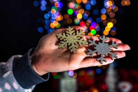 Holding Christmas snowflake decoration isolated on background with blurred lights. December season, Christmas composition.