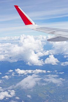 View of land, sky, cloud and wing of airplane from window