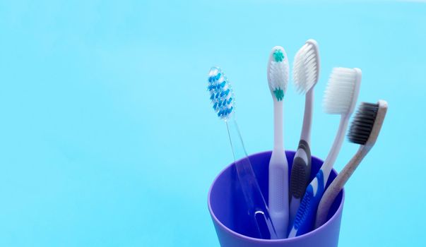 Toothbrushes in plastic glass on blue background. Copy space