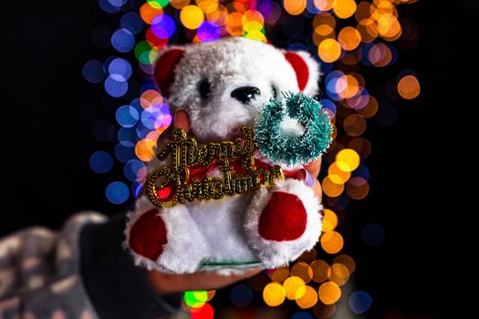 Holding Christmas decoration isolated on background with blurred lights. December season, Christmas composition.