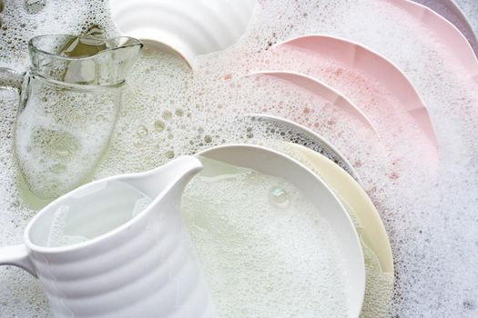 Washing dishes, Close up of utensils soaking in kitchen sink.