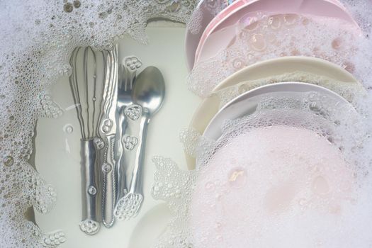 Washing dishes, Close up of utensils soaking in kitchen sink.