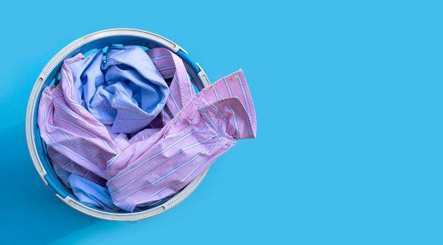 Clothes in a laundry basket on blue background.