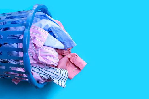 Clothes with a laundry basket on blue background. Copy space