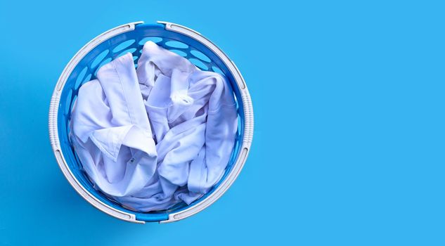 White clothes in a laundry basket on blue background.