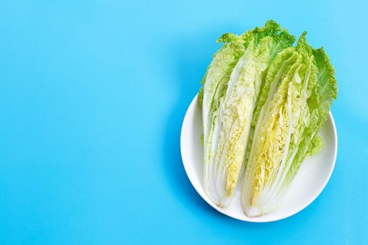 Chinese cabbage cut on  white plate on blue background. Top view