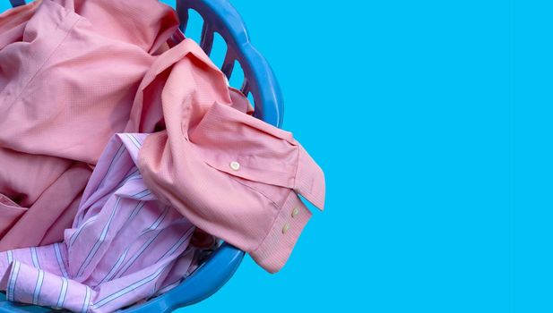 Clothes in a laundry basket on blue background. Copy space