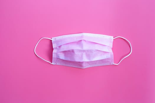 Pink protective medical mask on pink background. Top view