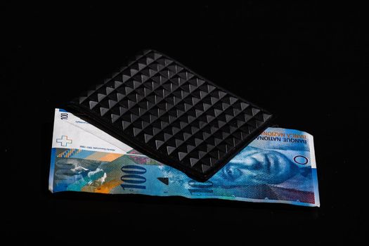 100 swiss franc banknote in a black wallet isolated.