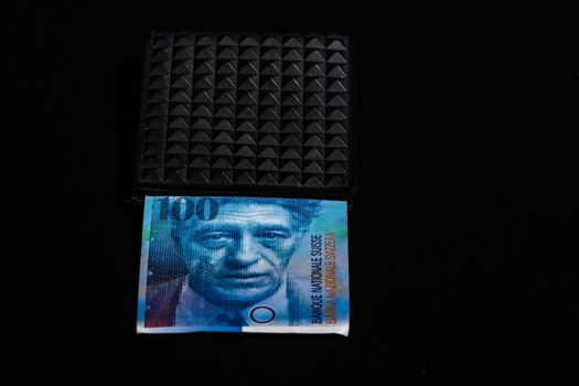 100 swiss franc banknote in a black wallet isolated.