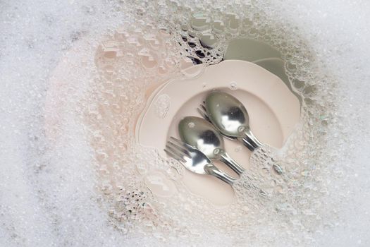 Washing dishes, Close up of utensils soaking in kitchen sink.