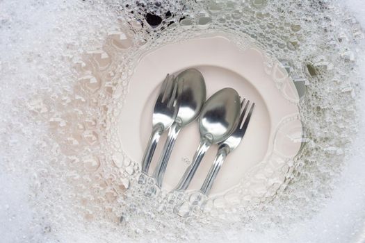 Washing dishes, Close up of utensils soaking in kitchen sink.