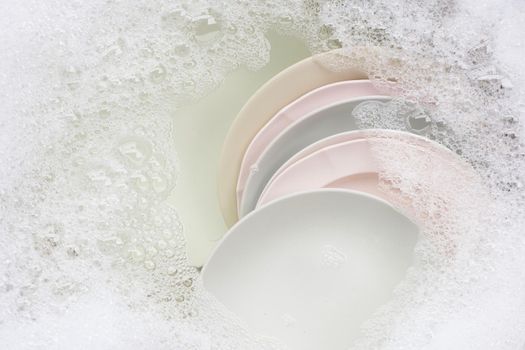 Washing dishes, Close up of utensils soaking in kitchen sink.