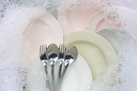 Washing dishes, Close up of utensils soaking in kitchen sink.