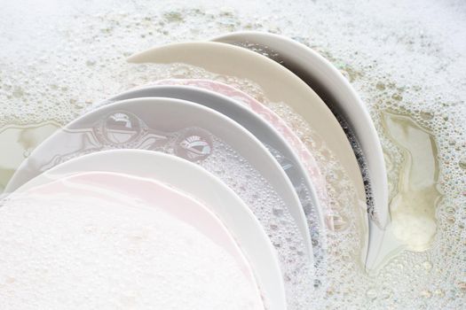 Washing dishes, Close up of utensils soaking in kitchen sink.