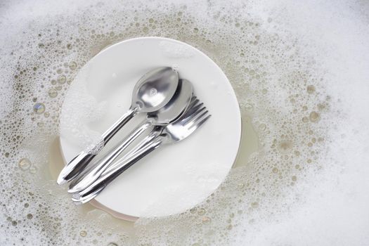 Washing dishes, Close up of utensils soaking in kitchen sink.