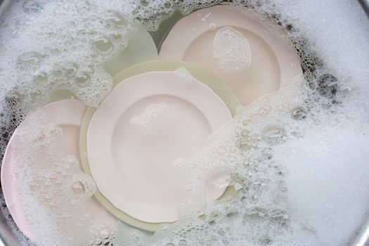 Washing dishes, Close up of utensils soaking in kitchen sink.