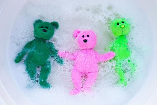 Soak toy bears in laundry detergent water dissolution before washing.  Laundry concept, Top view