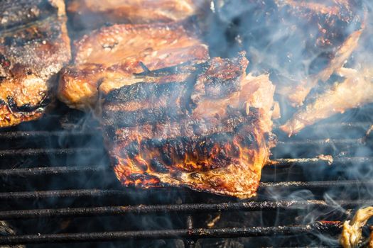 Grilled mackerel fish with smoke on a charcoal barbecue grill.