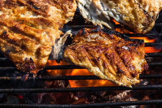 Grilled mackerel fish with smoke on a charcoal barbecue grill.