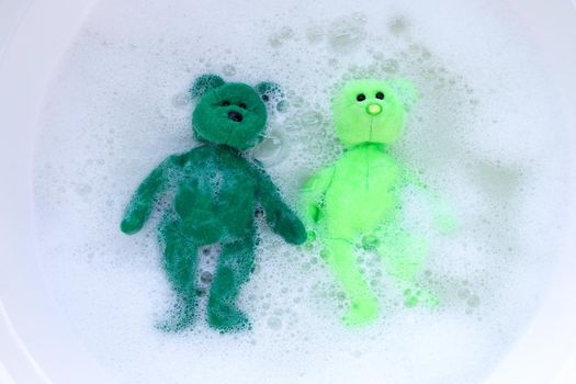 Soak toy bears in laundry detergent water dissolution before washing.  Laundry concept, Top view