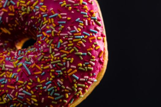 Pink glazed donut with sprinkles isolated. Close up of colorful donut.