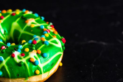 Green glazed donut with sprinkles isolated. Close up of colorful donut.