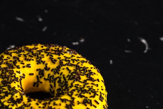 Yellow glazed donut with sprinkles isolated. Close up of colorful donut.