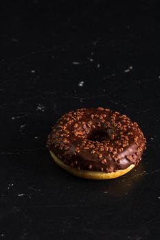 Chocolate glazed donut with chocolate chips isolated. Close up of delicious donut.