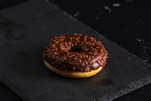 Chocolate glazed donut with chocolate chips isolated. Close up of delicious donut.