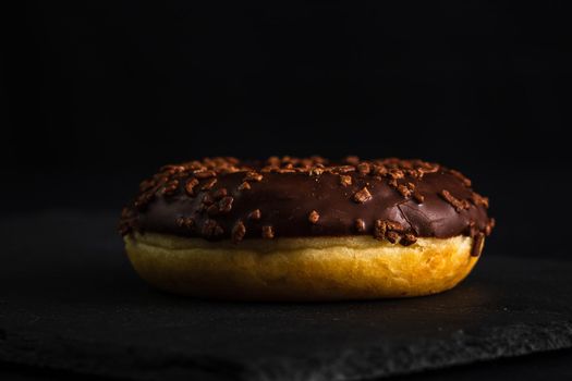 Chocolate glazed donut with chocolate chips isolated. Close up of delicious donut.