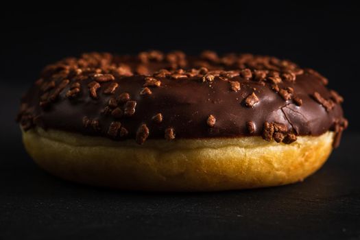 Chocolate glazed donut with chocolate chips isolated. Close up of delicious donut.