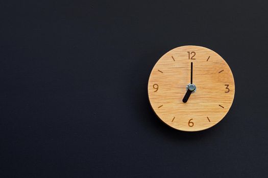 Wooden clock on dark background. Copy space