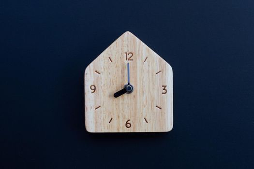 Wooden clock on dark background. Copy space