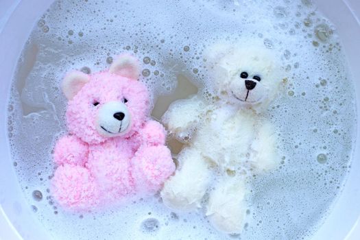 Soak toy bears in laundry detergent water dissolution before washing.  Laundry concept, Top view