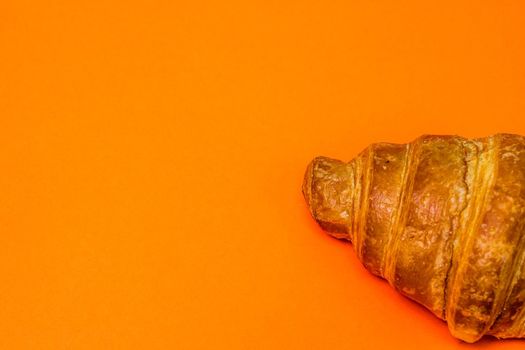 Fresh croissant isolated on orange board. French breakfast concept.