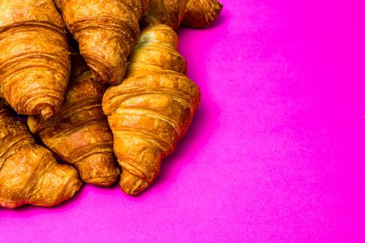 French breakfast concept. Close up of delicious, fresh croissants isolated on pink board.