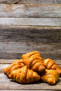 Delicious, fresh croissants isolated on wooden board. French breakfast concept.