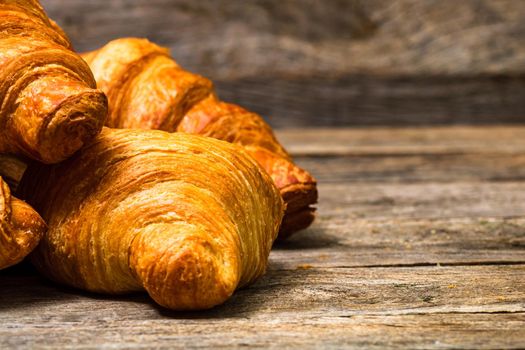 Delicious, fresh croissants isolated on wooden board. French breakfast concept.