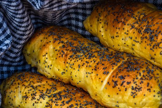 Sausages baked in dough sprinkled with salt and poppy seeds in a rustic composition. Sausages rolls, delicious homemade pastries.