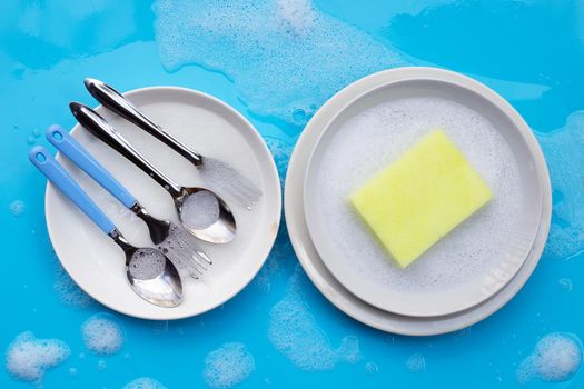 Washing dishes concept. wet blue with soapy foam background.