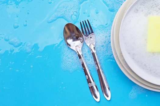 Washing dishes concept. wet blue with soapy foam background.