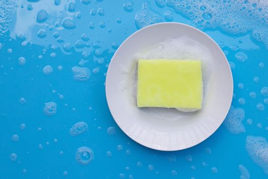 Washing dishes concept. wet blue with soapy foam background.