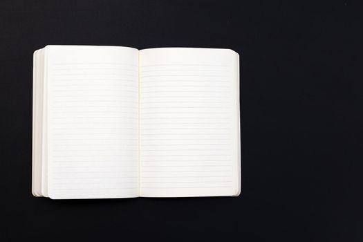 Open notebook on dark background. Top view