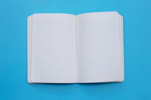 Open notebook on blue background. Top view