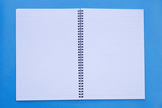 Open notebook on blue background. Top view