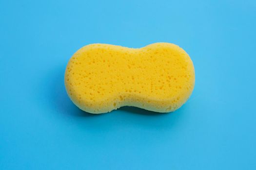 Yellow sponge on blue background.  Copy space