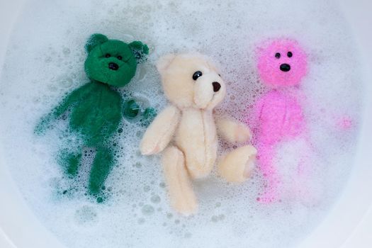 Soak toy bears in laundry detergent water dissolution before washing.  Laundry concept, Top view