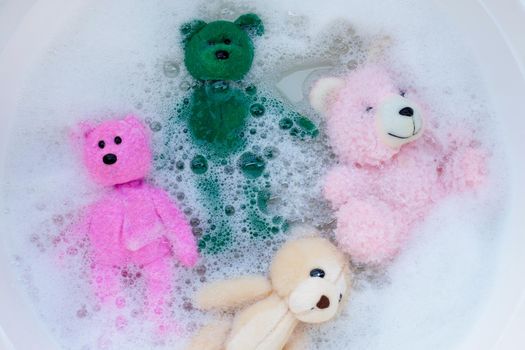 Soak toy bears in laundry detergent water dissolution before washing.  Laundry concept, Top view