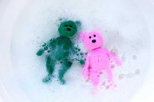 Soak toy bears in laundry detergent water dissolution before washing.  Laundry concept, Top view